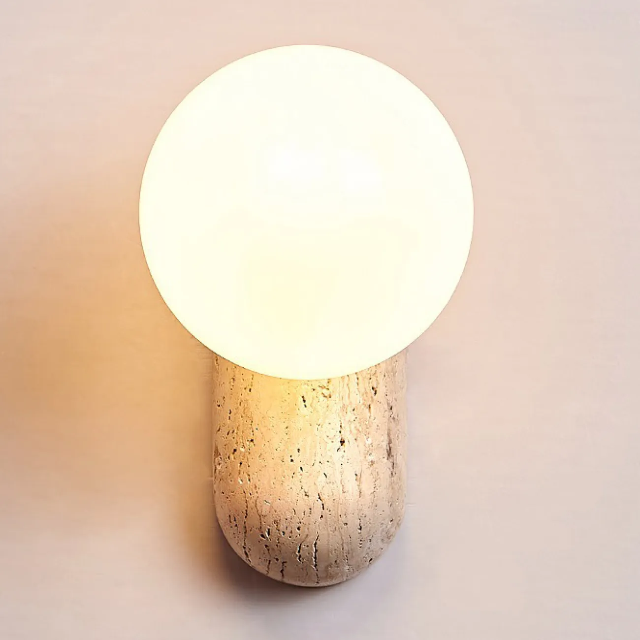 Настенный светильник с шарообразным стеклянным плафоном на округлом основании из камня травертина JONTE