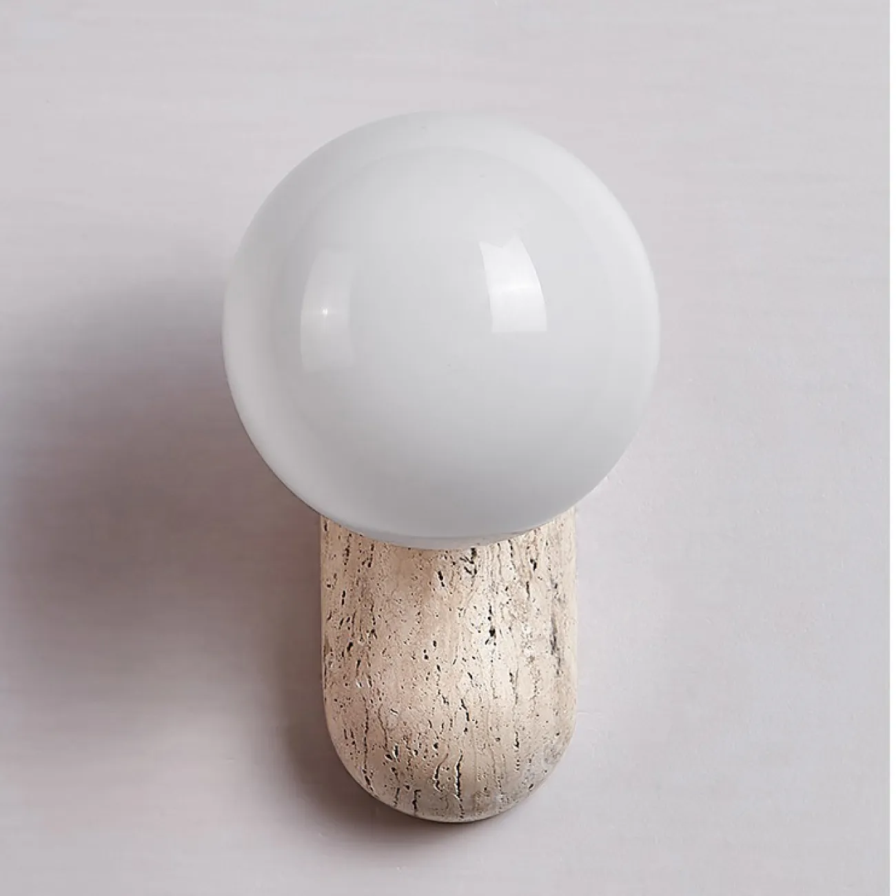 Настенный светильник с шарообразным стеклянным плафоном на округлом основании из камня травертина JONTE